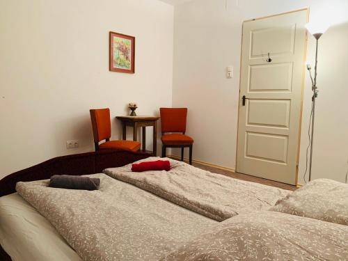 a bedroom with two beds and a door and chairs at Home of arts and creation, Erdei alkoto studio in Verőce
