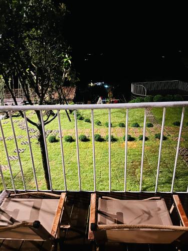a balcony with two chairs and a fence at Giăng's House Farmstay & Glamping in Bao Loc