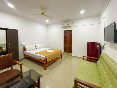 a bedroom with a bed and a couch and a tv at AWA Residency in Cochin