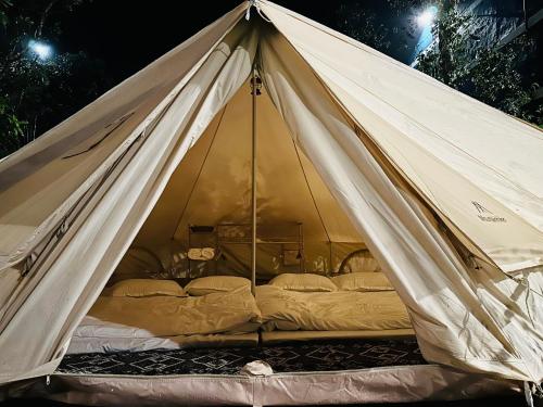 a large white tent with beds in it at night at Giăng's House Farmstay & Glamping in Bao Loc