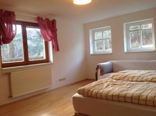 a bedroom with a bed and two windows at Charmantes Landhaus mit Garten und traumhaftem Fernblick in Thal