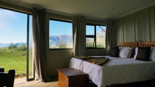 een slaapkamer met een bed en uitzicht op de bergen bij Witsieshoek Mountain Lodge in Phuthaditjhaba