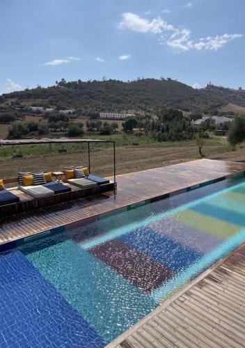 a swimming pool with chairs and a view of a field at Viva! Farmhouse in Monsaraz