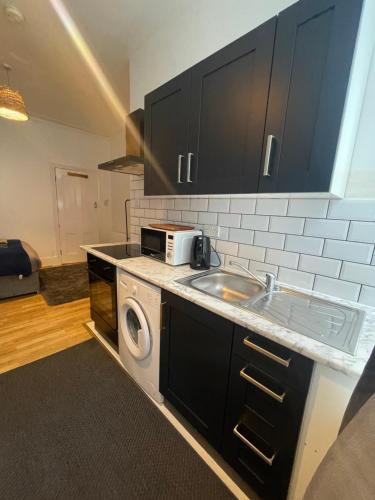 a kitchen with a sink and a microwave at 10 Minutes to Wembley Guest Studios in London