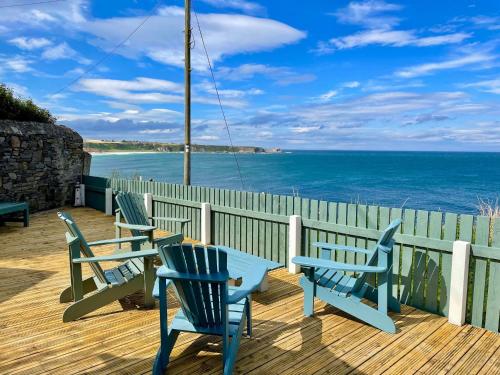 Tres bancos azules sentados en una terraza con vistas al océano. en Hill Crest - cliff top cottage with stunning views, en Cullen