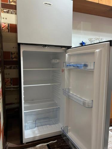 an empty refrigerator with its door open in a kitchen at Welcome TJ Apartment in Khujand