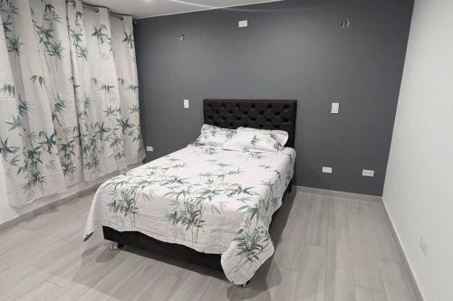 een slaapkamer met een bed met een deken en gordijnen bij Espacioso departamento en cayma in Cayma