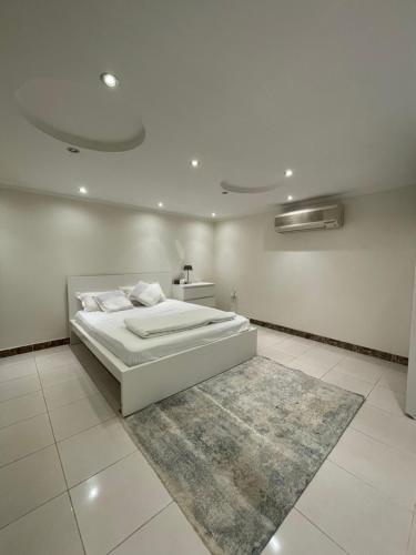 a white bedroom with a bed and a rug at شقة فاخرة بقفل ذكي - Luxury apartment in Riyadh