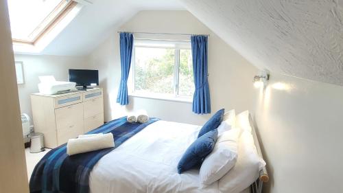 a bedroom with a bed with blue curtains and a window at Birchcroft Hideaway in Ferndown