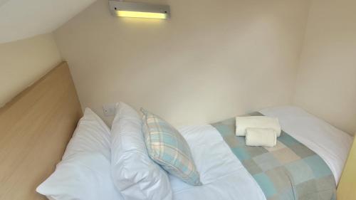 a bed with white sheets and pillows in a room at Birchcroft Hideaway in Ferndown