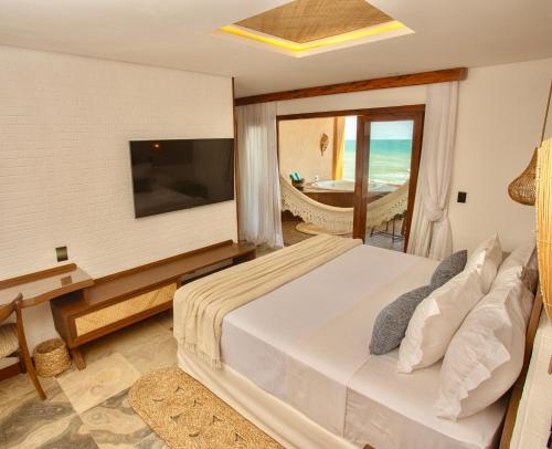 ein Schlafzimmer mit Bett und Fernseher und Balkon in der Unterkunft Carlore Hotel Taíba in Taíba