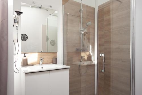 uma casa de banho com um chuveiro, um lavatório e um espelho. em Villa Tania em Allauch