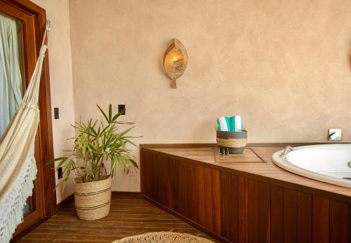 baño con bañera, lavamanos y planta en Carlore Hotel Taíba, en Taíba