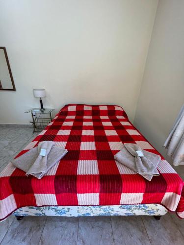 uma cama com um cobertor xadrez vermelho e branco em Apartamento Río y Selva em Puerto Iguazú