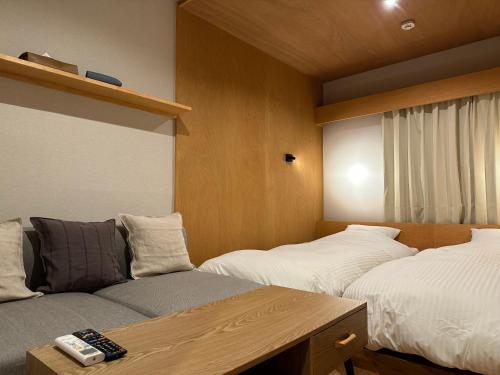 ein Zimmer mit 2 Betten und einem Sofa darin in der Unterkunft Lake Side Inn MIRAHAKONE in Moto-hakone