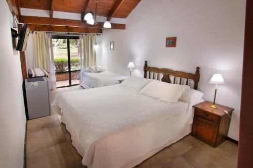 a bedroom with two white beds and a window at Hostal La Merced in Villa General Belgrano