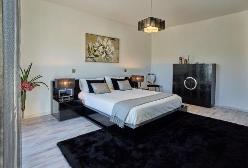 um quarto com uma cama grande com lençóis brancos e almofadas em Fonte Seca GuestHouse em Leiria