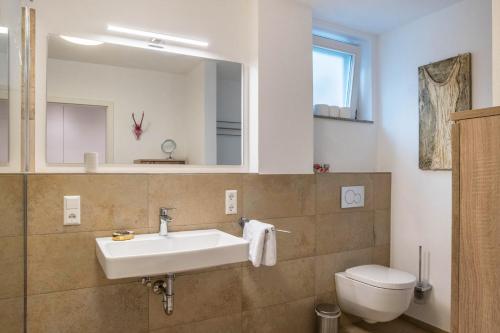 a bathroom with a sink and a toilet and a mirror at Ferienwohnung Tödiblick in Wangen im Allgäu