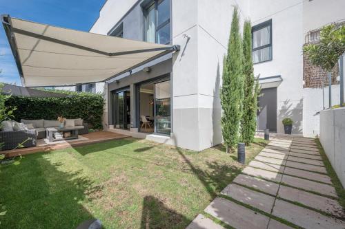 um quintal com um relvado com um grande guarda-chuva em LUJOSO CHALET CON PISCINA PRIVADA, JARDIN Y DOMÓTICA EN PUERTA DE HIERRO em Madri