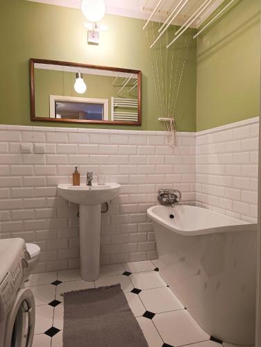 a bathroom with a sink and a tub and a mirror at Apartament Parkowy 24h in Łomża