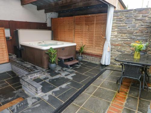 a hot tub sitting on a patio with a table at Y Cartws in Eglwyswrw