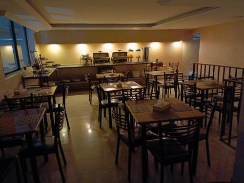 a restaurant with tables and chairs and a kitchen at Rayan Hotel Suites in Amman