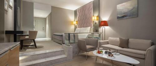 a living room with a couch and a room with a bed at Elexus Hotel Resort & Spa & Casino in Kérynia