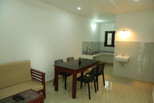 a living room with a table and chairs and a sink at Grace Mary Residency in Nedumbassery