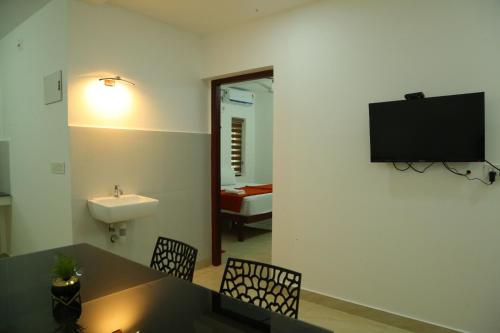 a bathroom with a sink and a tv on the wall at Grace Mary Residency in Nedumbassery