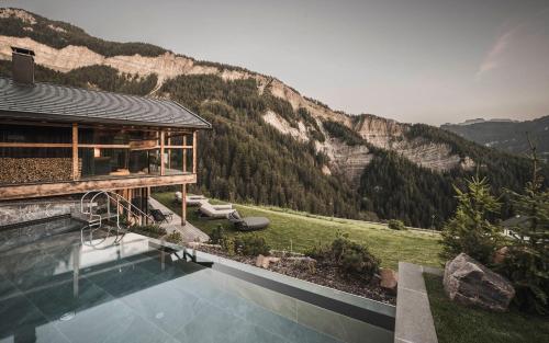 a house with a swimming pool in front of a mountain at Luxury Chalet Vilaiet in Ortisei