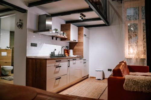 uma cozinha com armários brancos e um sofá num quarto em Apartman Saturn em Osijek