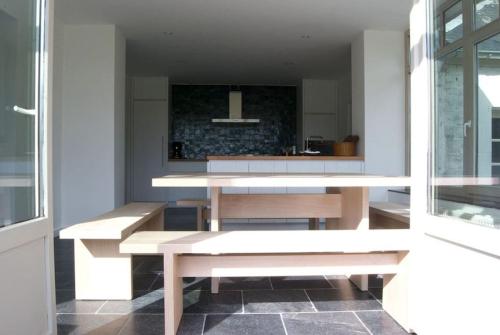 a dining room with two benches and a kitchen at Le Chaperon Villa in Tellin