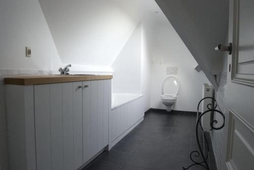a white bathroom with a sink and a toilet at Le Chaperon Villa in Tellin