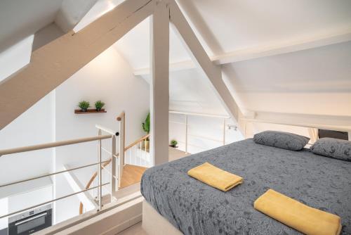 un dormitorio en el ático con una cama y una escalera en The Fashion Street Residence en Amberes
