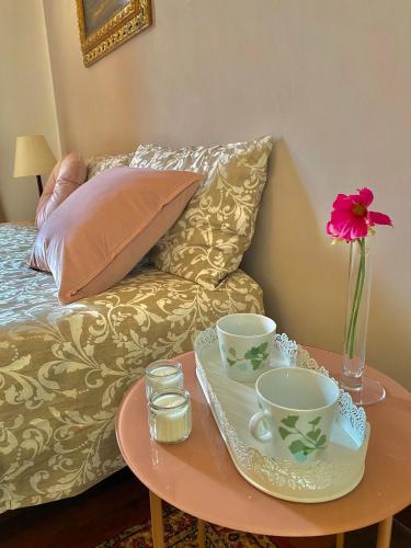 a coffee table with two cups and a vase with a flower at Le Camere di Mara in Foligno