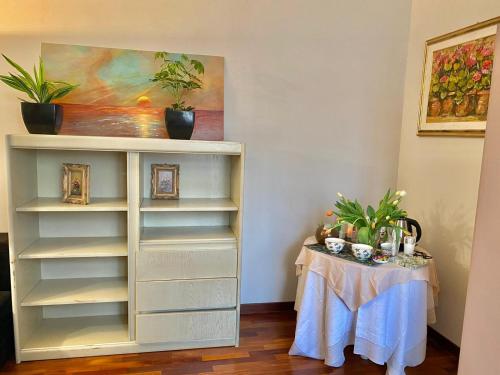 a white book shelf with a table with plants on it at Le Camere di Mara in Foligno