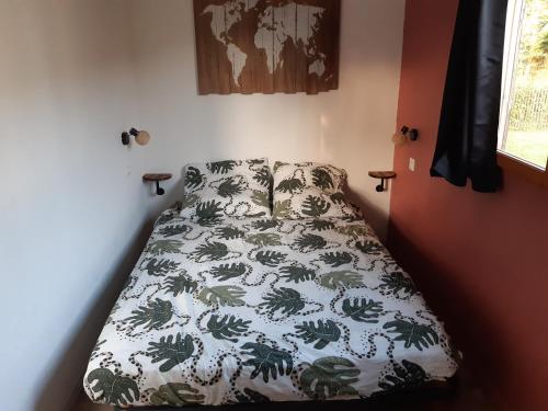 Bett in einem Zimmer mit einer Bettdecke mit Palmen in der Unterkunft chalet en bord de rivière (saône) in Rigny