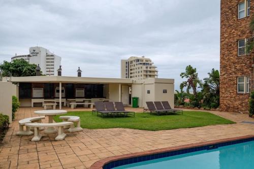 un patio con mesa, sillas y piscina en Sea Lodge G01 en Durban