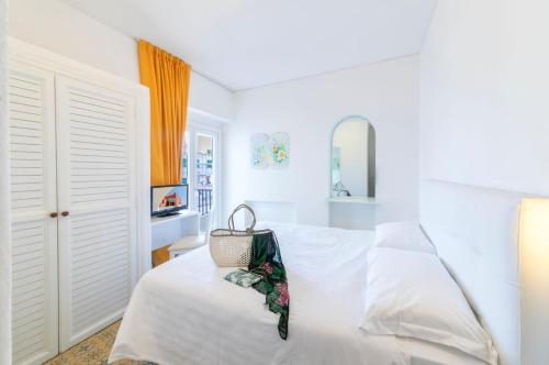 a white bedroom with a bed with a purse on it at Le Canne Family Resort & Spa in Ischia