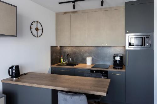 a kitchen with a table and a clock on the wall at Apartament LUX przy Pileckiego 34 in Biała Podlaska