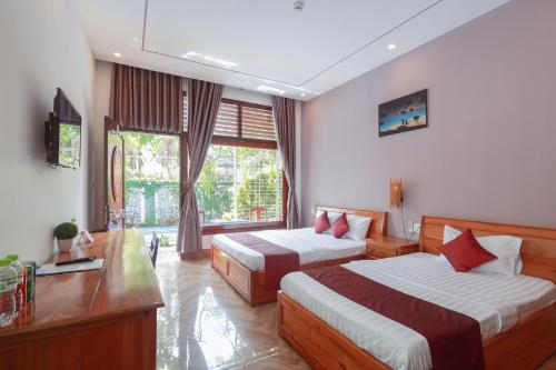 a hotel room with two beds and a desk at Hotel Blue Dragon in Phú Quốc