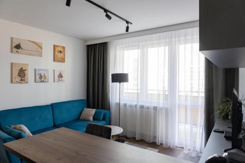 a living room with a blue couch and a table at Apartament LUX przy Pileckiego 34 in Biała Podlaska