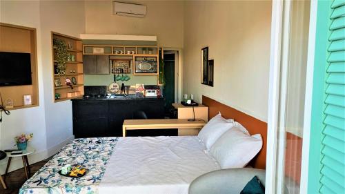 a small bedroom with a bed and a kitchen at Loft Veneto in Maringá
