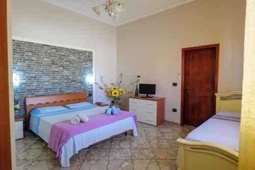 1 dormitorio con 2 camas, escritorio y TV en Casa Aurora Luxury Apartment, en Giuggianello
