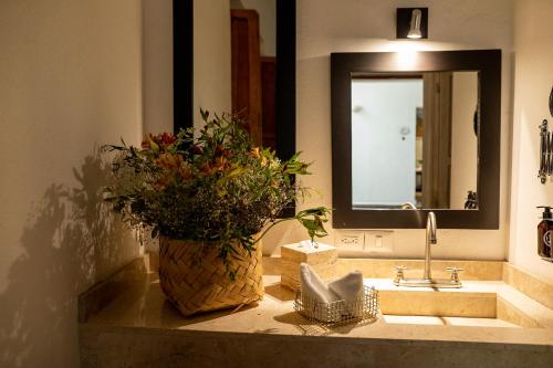 un baño con un jarrón de flores en un fregadero en Casa Aspeytia Hotel Boutique, en Querétaro