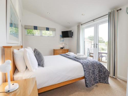 a bedroom with a large white bed and a window at 9 Valley View in Looe