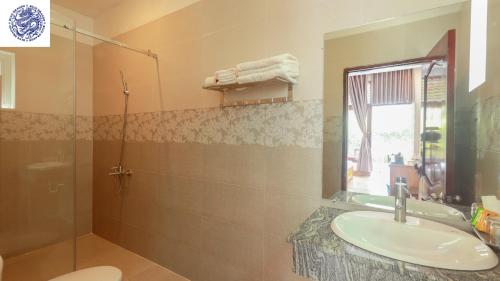 a bathroom with a sink and a shower and a mirror at Hotel Blue Dragon in Phú Quốc
