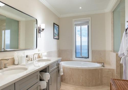 a bathroom with two sinks and a tub and a window at Scrub Island Resort, Spa & Marina in The Mill