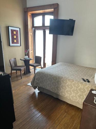 a bedroom with a bed and a table and chairs at Casa Aspeytia Hotel Boutique in Querétaro