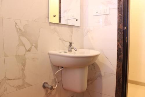 y baño con lavabo blanco y espejo. en Hotel Sai Ramanand, en Shirdi